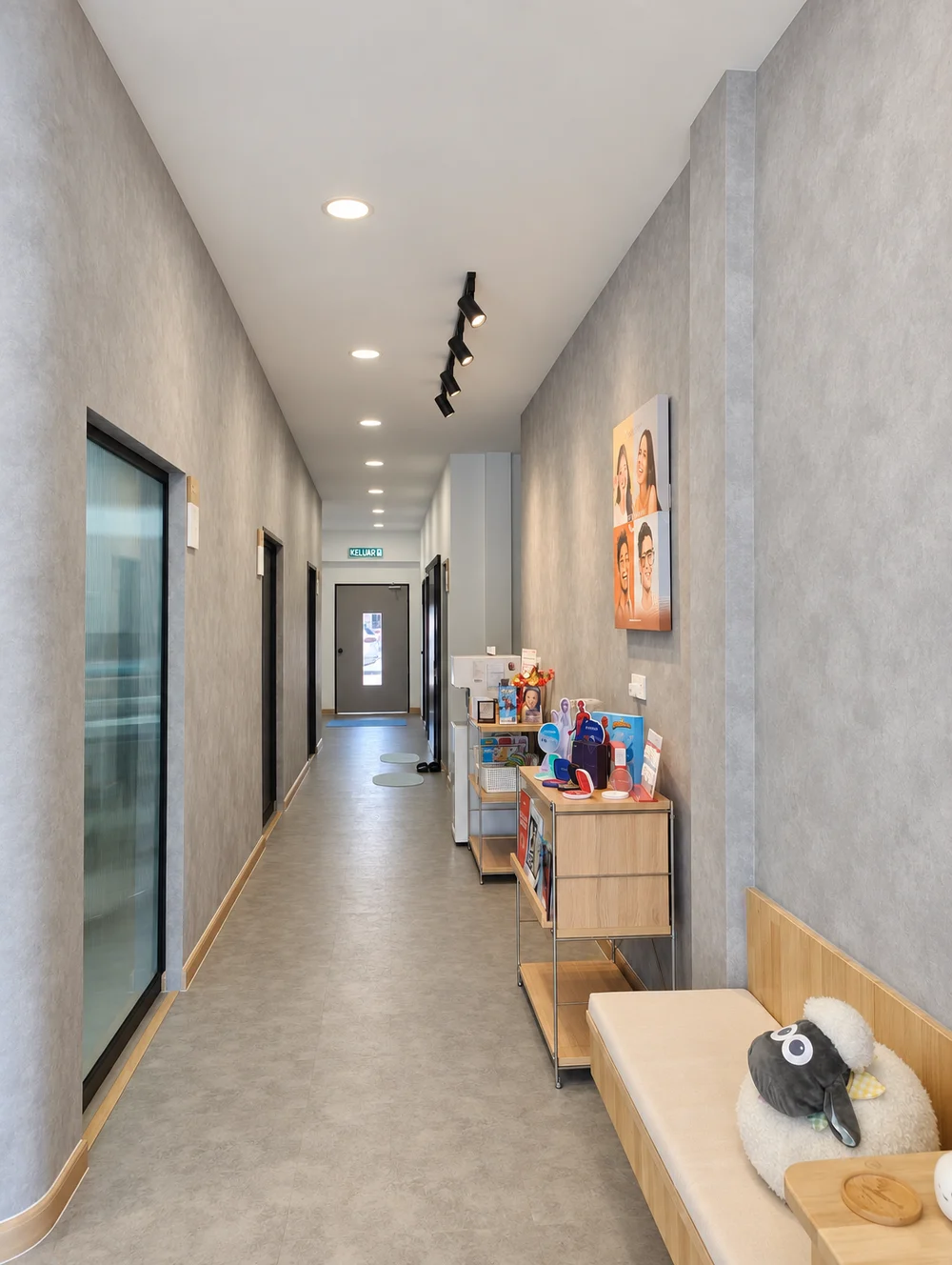 The clinic's bright corridor with treatment room doors and a waiting bench with a soft toy